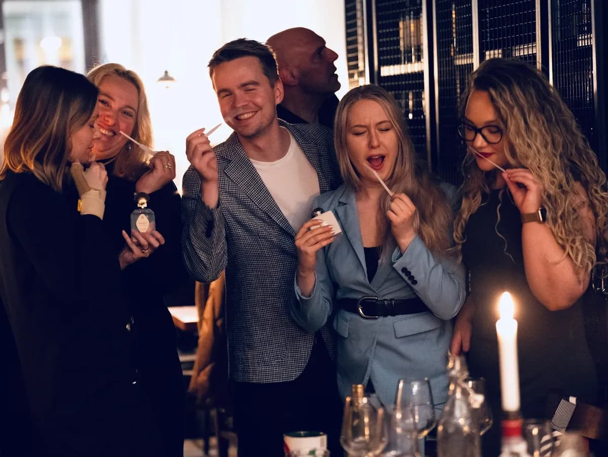 Group of perfume lovers trying new perfumes in a candlelit restaurant