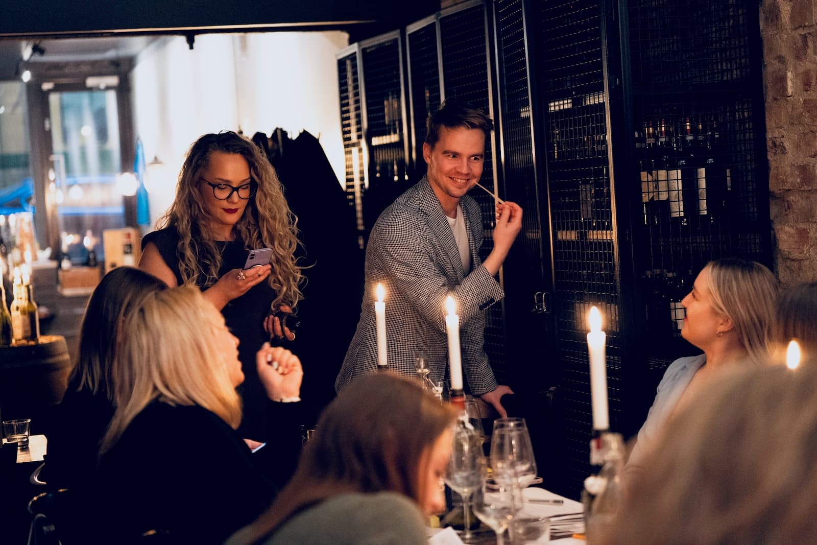 A host with a scent strip standing among guests at the table