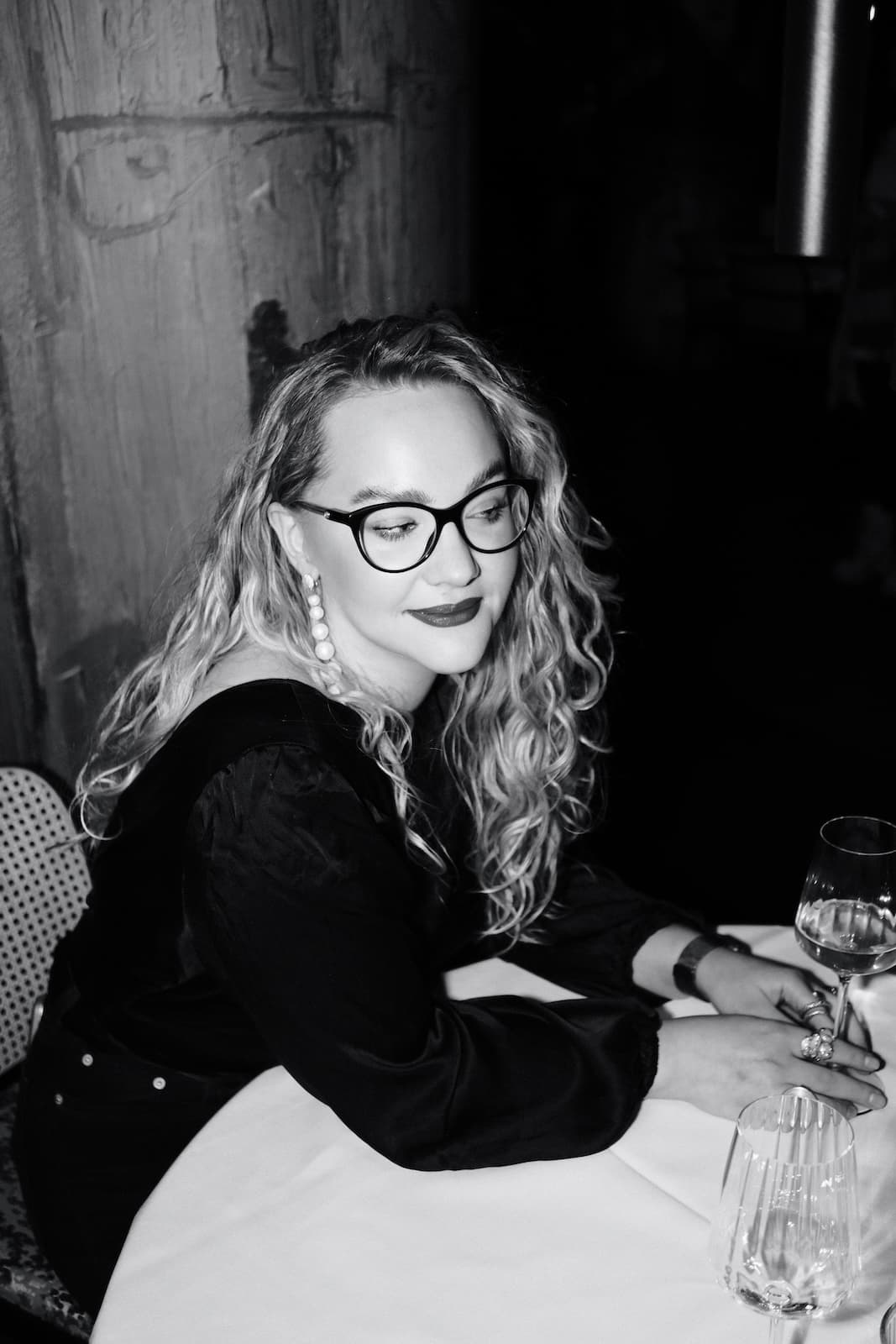 A guest with a glass of wine at a candlelit table during a club evening